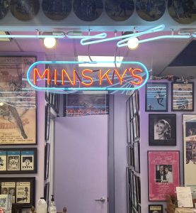 A neon sign hangs from the ceiling and says Minsky's.