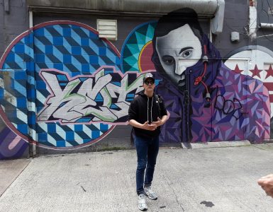 Cory Stowers standing in front of graffiti on a wall